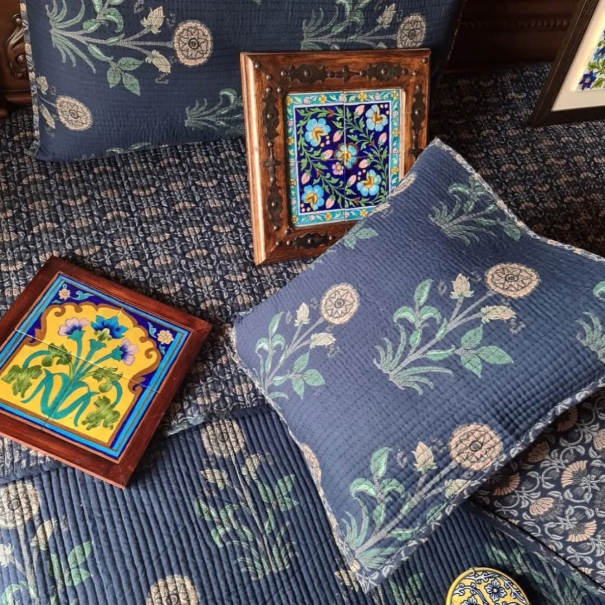 Decorative pillows and tiles with floral patterns on a textured surface
