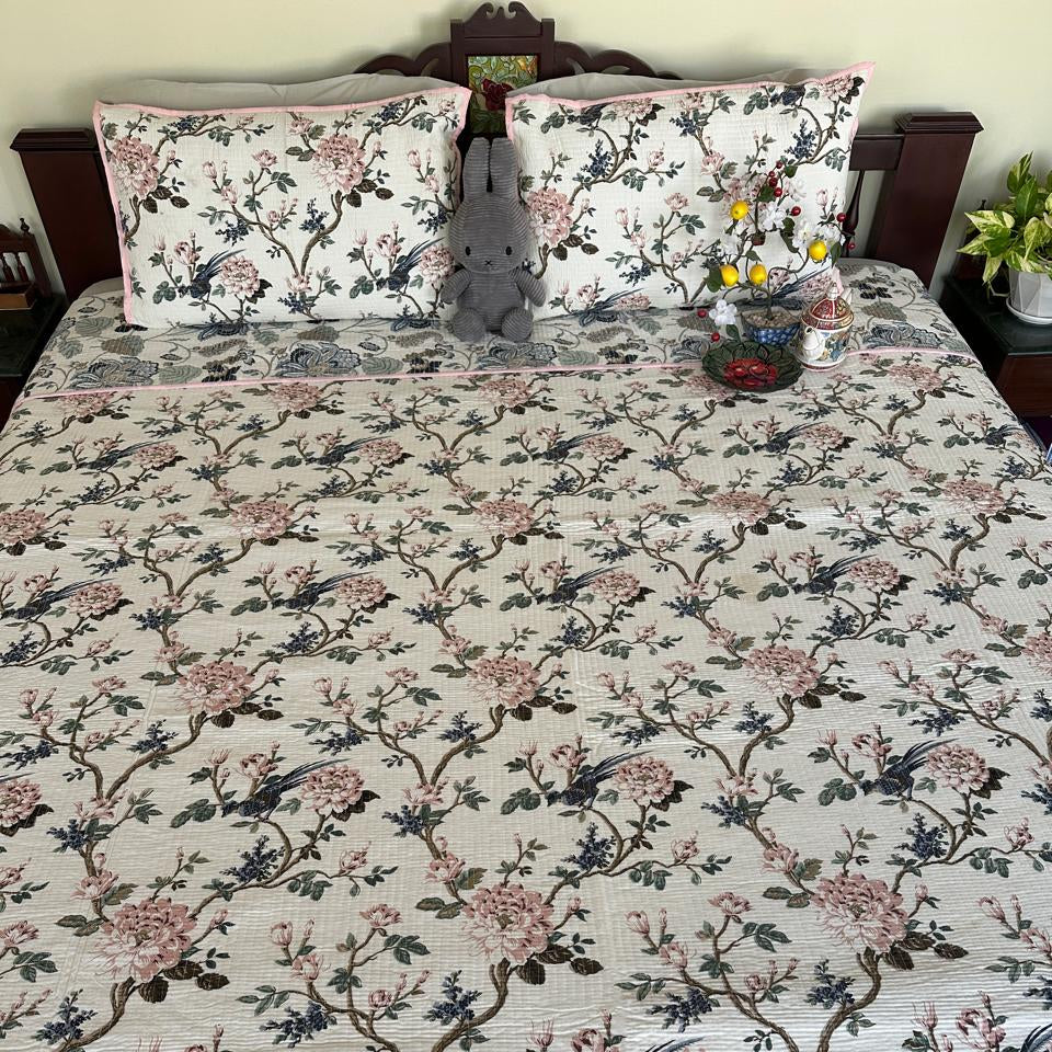 Floral patterned bedspread on a bed with matching pillows.