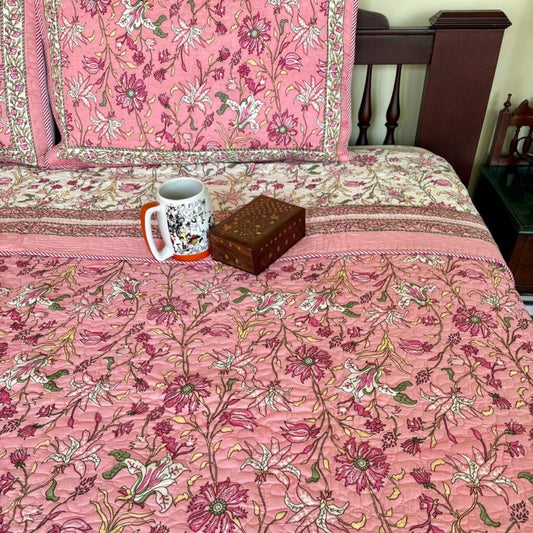 Pink floral bedspread with a mug and box on a bed
