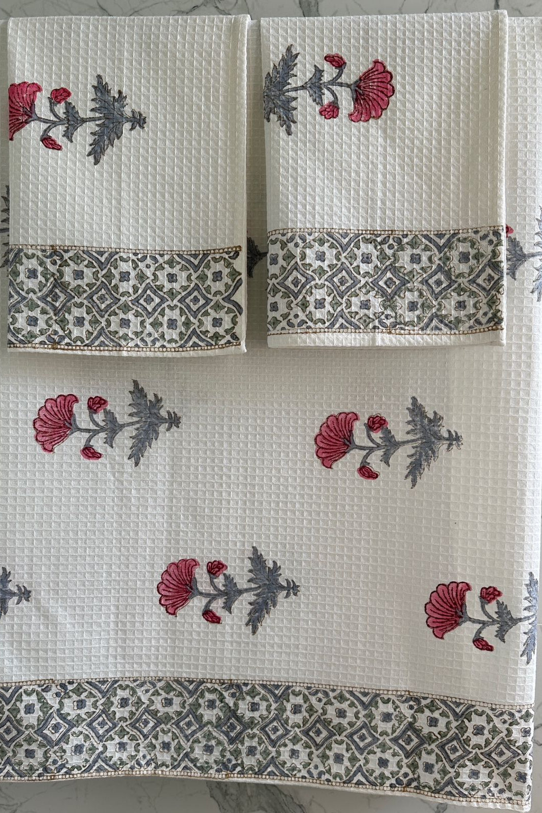 Set of three towels with floral and geometric patterns on a neutral background