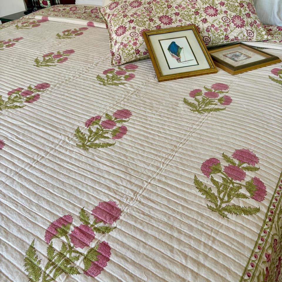 Floral-patterned bedspread on a bed with framed pictures and pillows.