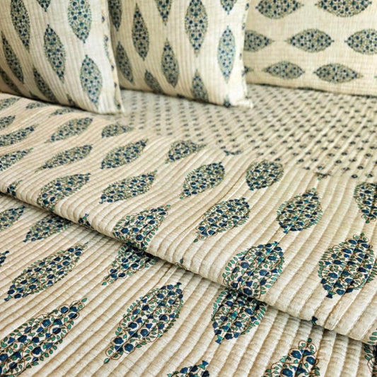 Close-up of patterned fabric with blue and green leaf designs on a beige background