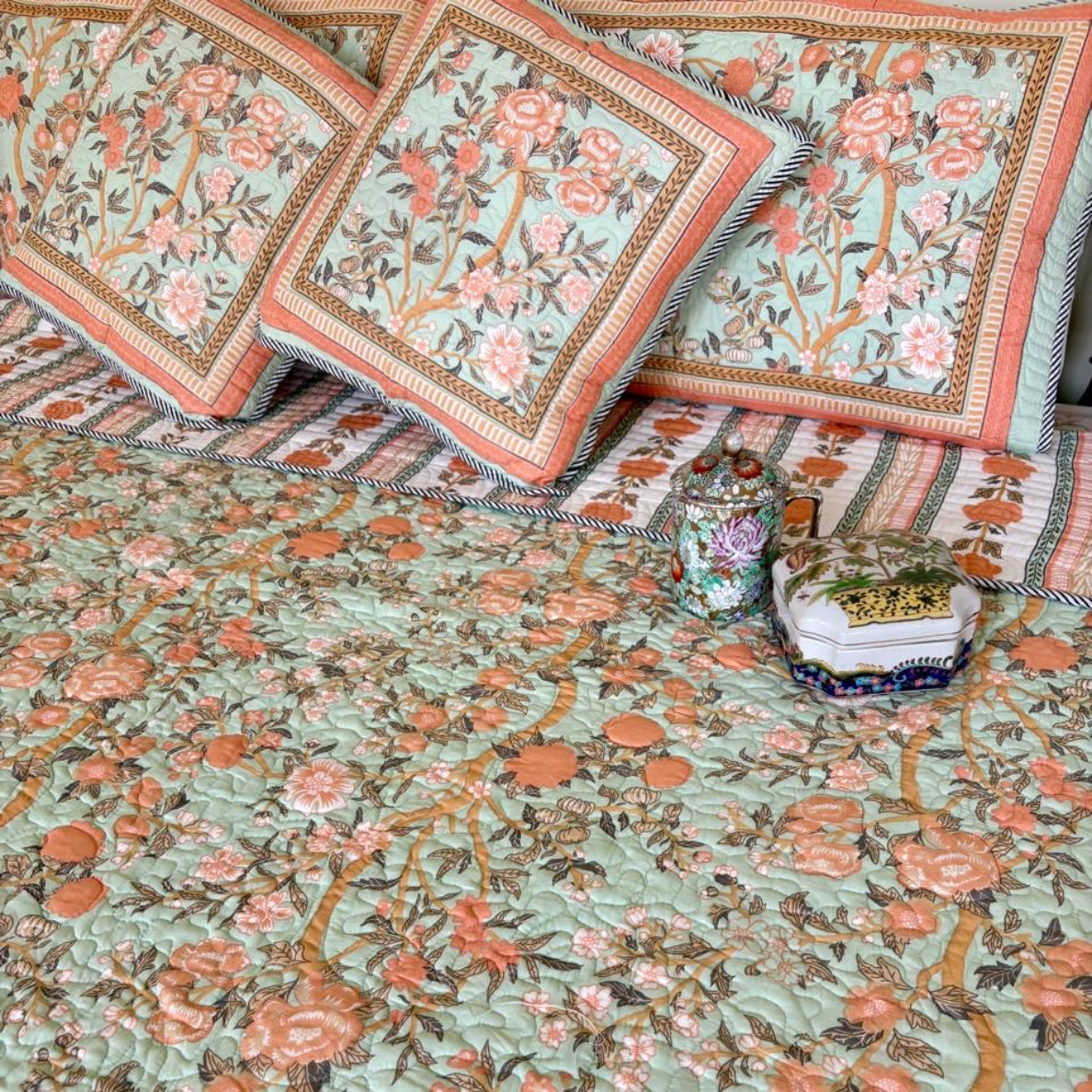 Floral patterned quilt with matching pillows on a bed.