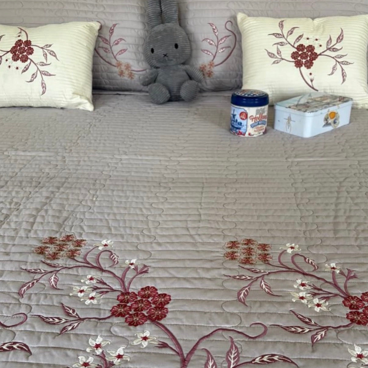 Gray sofa with floral-patterned cushions and a small gray stuffed animal.