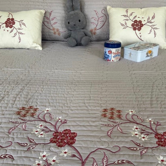 Gray sofa with floral-patterned cushions and a small gray stuffed animal.