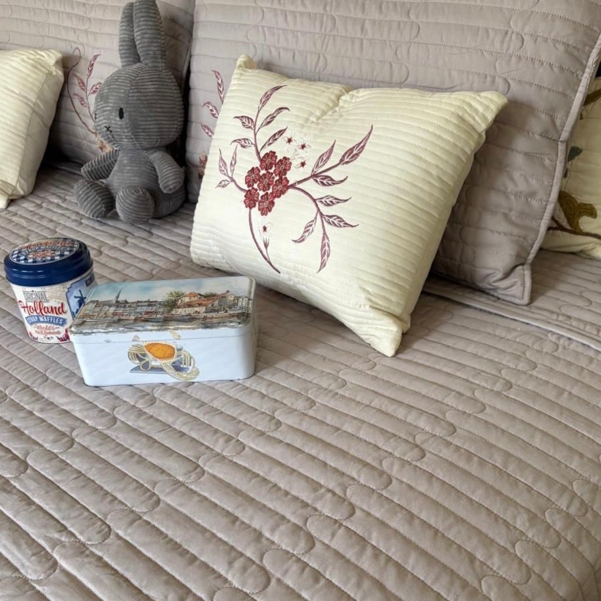 Beige sofa with decorative pillows and a container on a light-colored surface