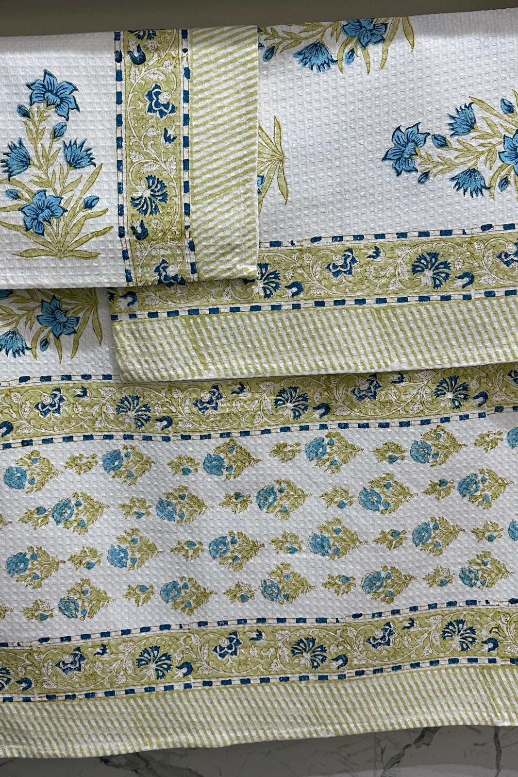 Set of floral-patterned tablecloths with green and blue designs on a white background.