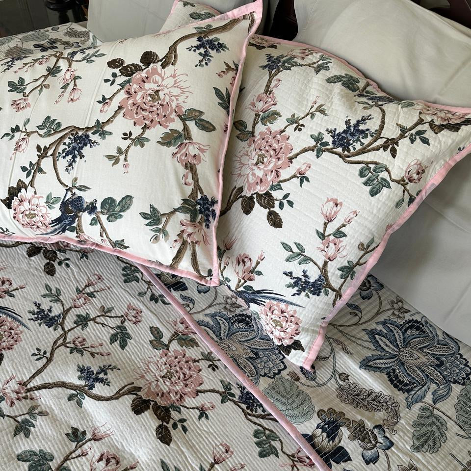 Floral patterned bedding with matching pillows on a bed.