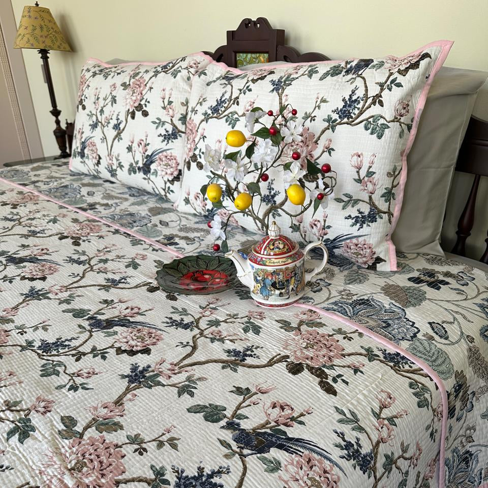 Floral patterned bedspread on a bed with decorative items.