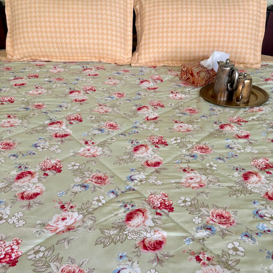 Floral patterned bedspread on a bed with two pillows and a tissue box.