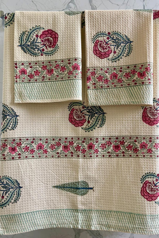Set of three decorative towels with floral patterns on a gray background