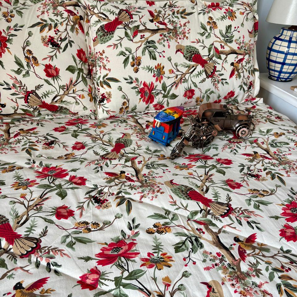 Floral and bird patterned bedding with toys on a bed.