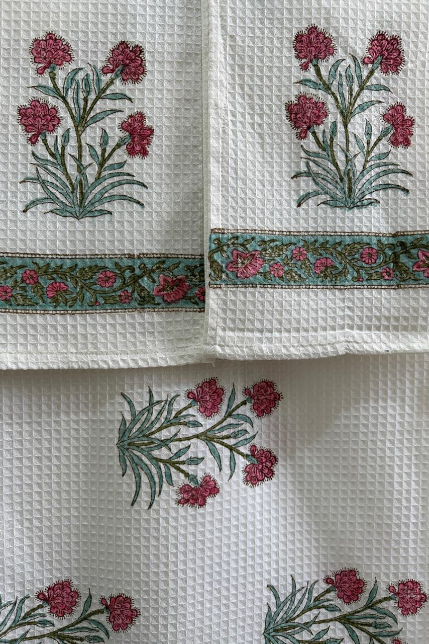 White towels with floral embroidery and decorative border on a white background