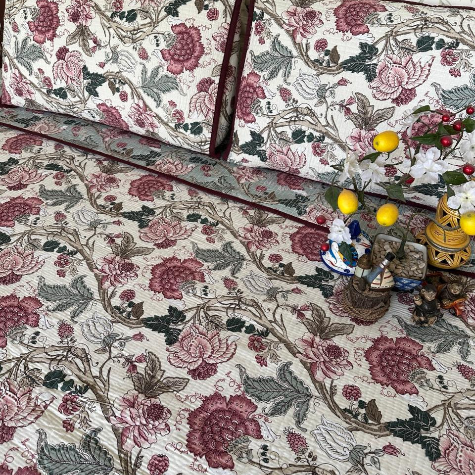 Floral patterned bedspread with matching pillows on a bed.