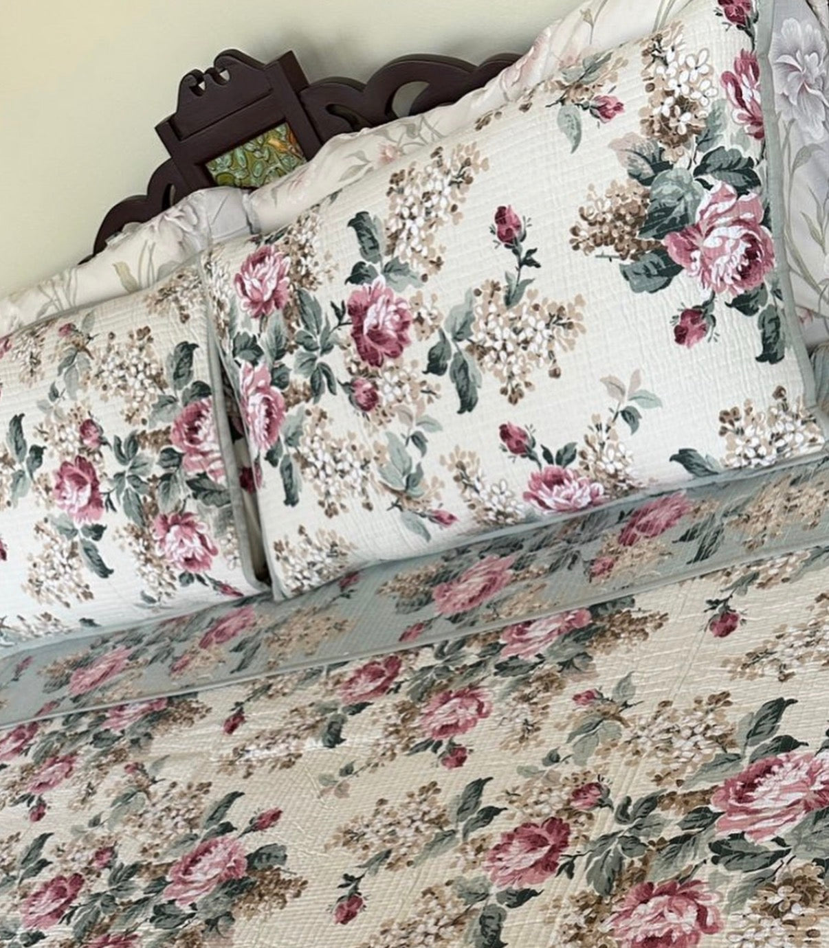 Floral patterned bedding set on a bed with a wooden headboard.