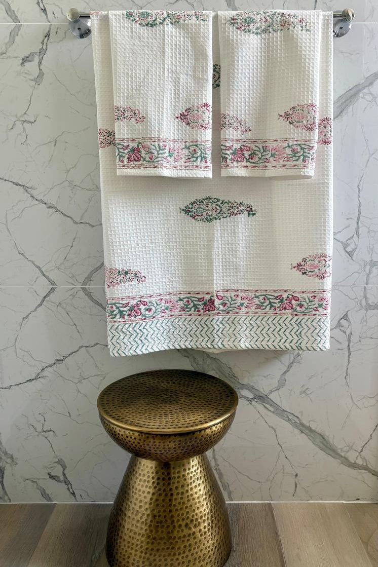 Floral-patterned towel hanging on a rack with a marble wall background
