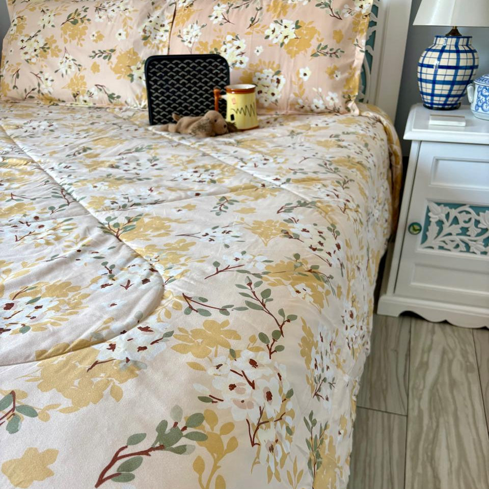 Floral patterned bedspread on a bed with a nightstand in the background