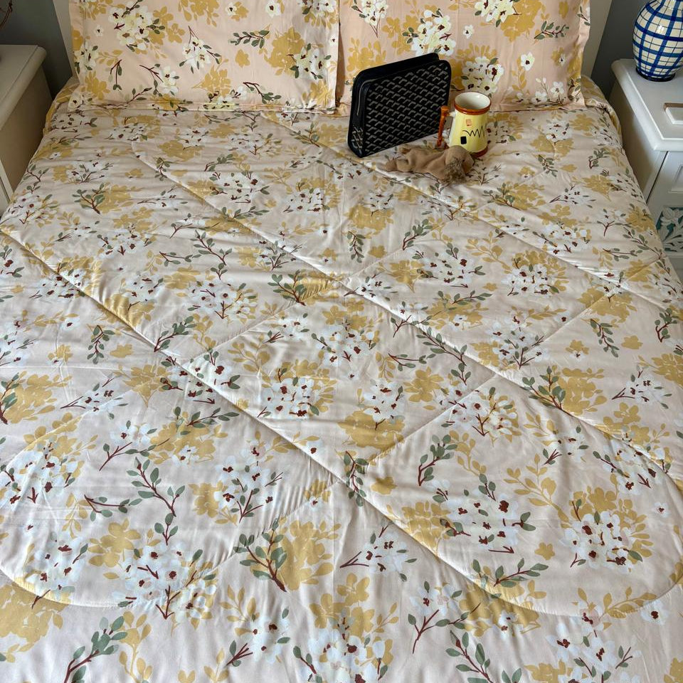 Floral-patterned bedspread on a bed with a nightstand in the background