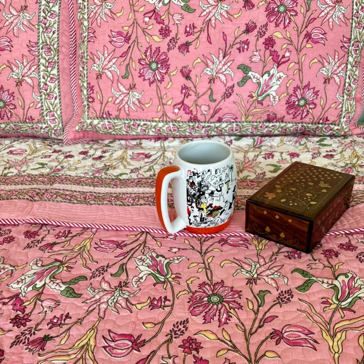 Mug and wooden box on a floral-patterned pink fabric