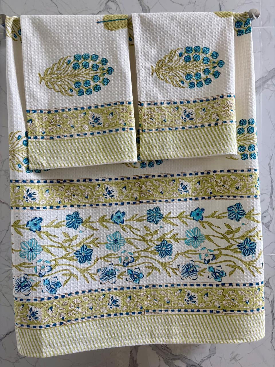 Set of three decorative towels with floral patterns on a marble surface