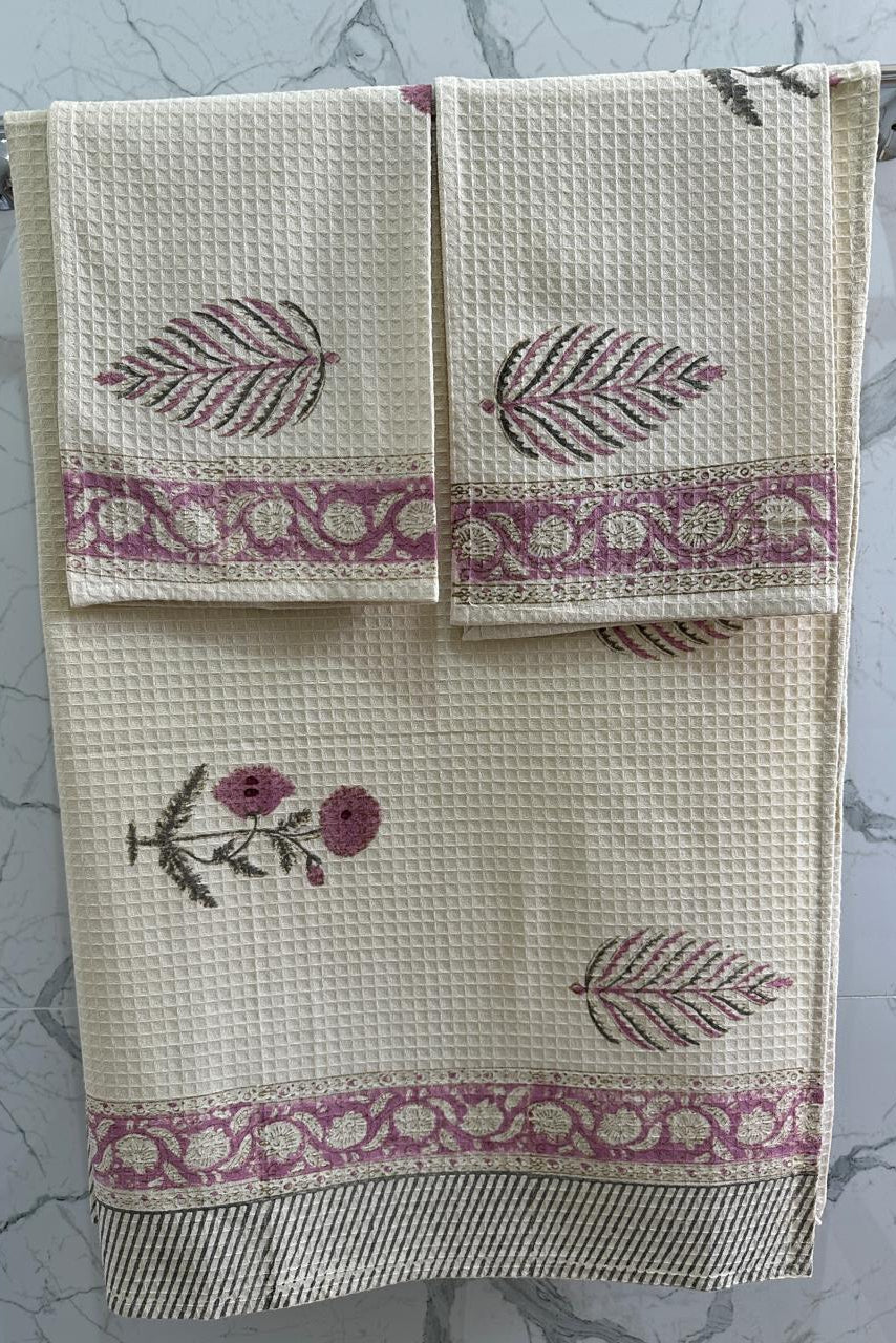 Set of three towels with floral and leaf patterns on a marble surface