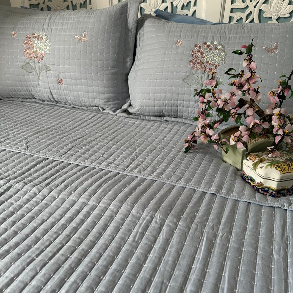Gray quilted sofa cover with floral decorations on a decorative wall background