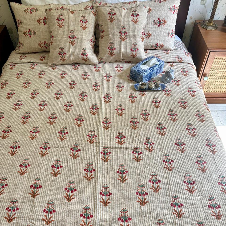 Floral patterned bedspread on a bed with matching pillows.
