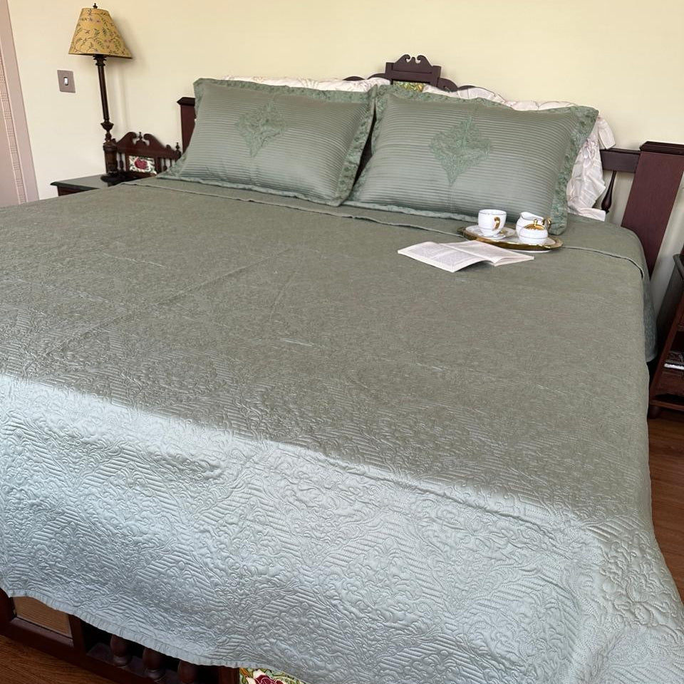 Bed with green bedding and pillows in a bedroom setting.