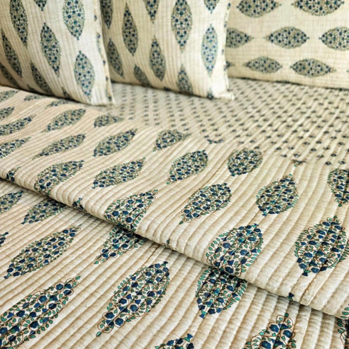 Close-up of patterned fabric with blue and green leaf designs on a beige background